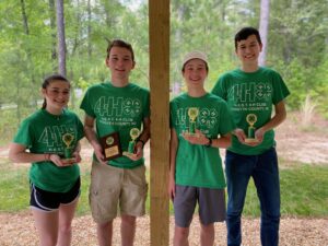 Four 4-H youth wearing green shirts, holding their 1st place trophies.